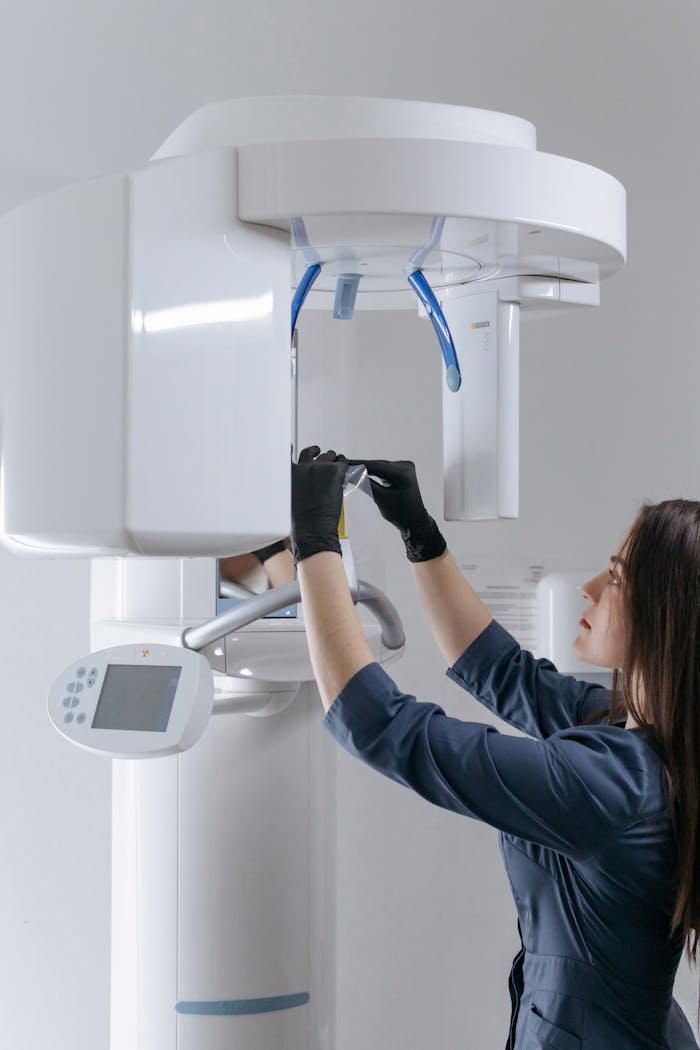 Female dental technician adjusting advanced x-ray machine at clinic.